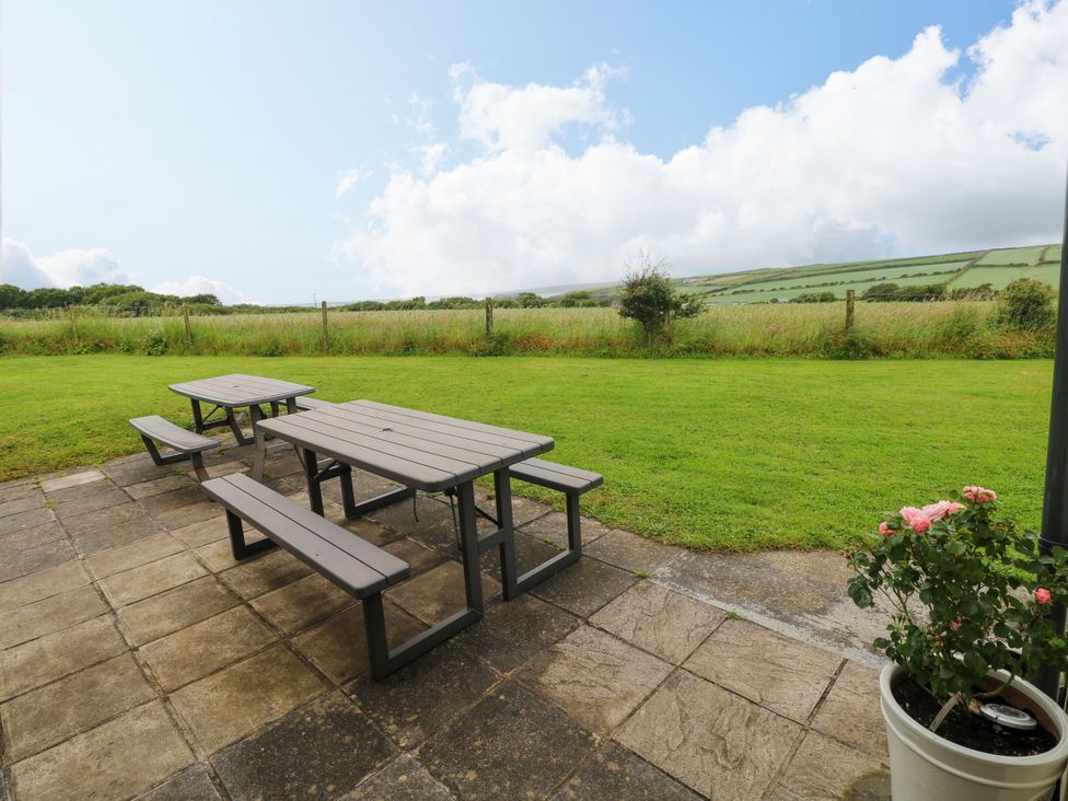 A table and benches on a patio area at North Studdock Cottage in Angle near Pembroke