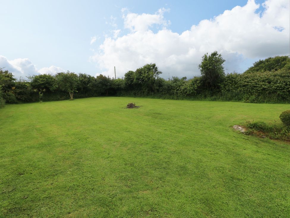 A garden with grass and a fire pit at North Studdock Cottage, Angle near Pembroke