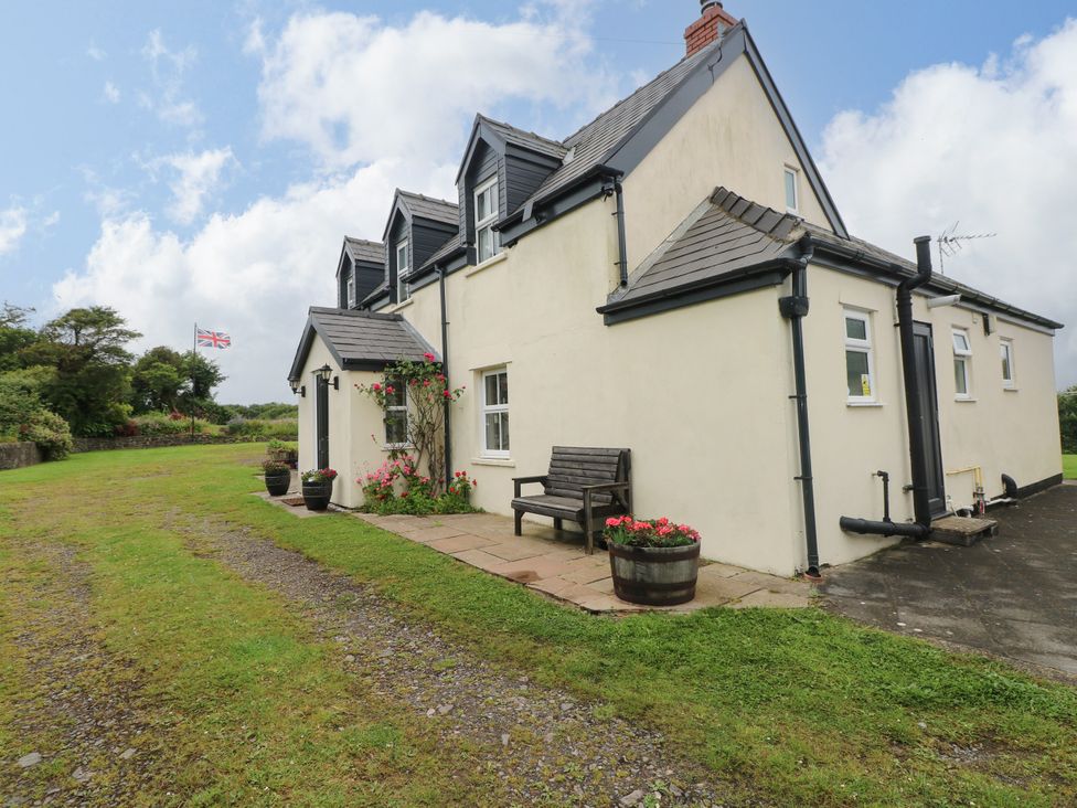 An outdoor view of a house with a bench and flower pots at North Studdock Cottage Angle near Pembroke