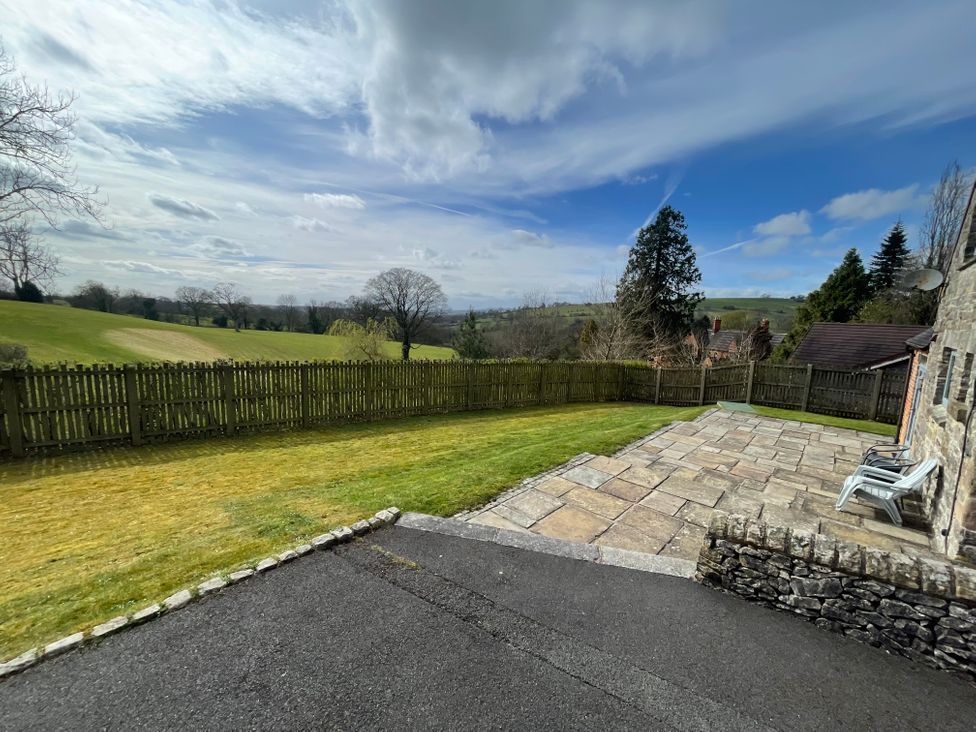 An outdoor view of a garden with a stone patio at Postbox Cottage in Atlow near Ashbourne