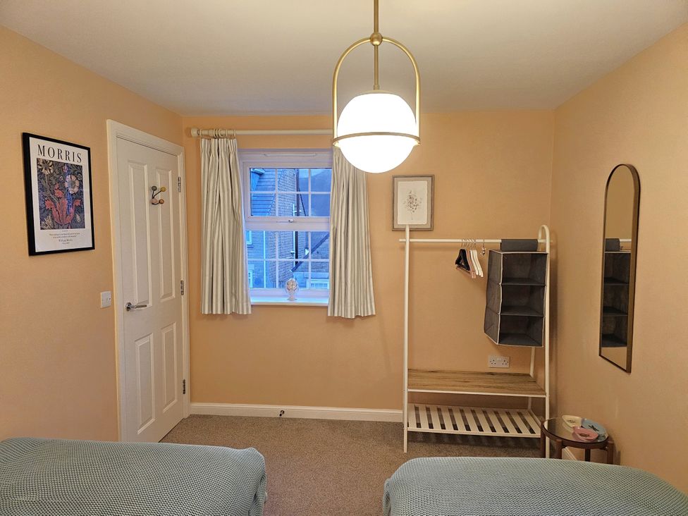 A bedroom with a bed, window, and clothes rack at The Milne in Todmorden