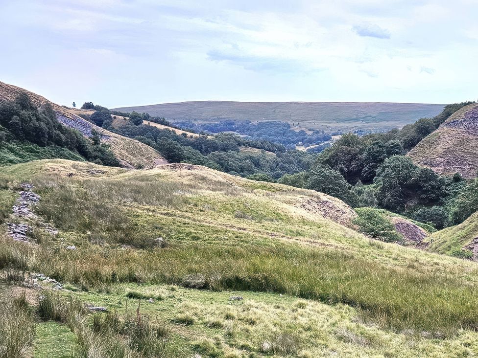 A landscape featuring hills and trees with a path in the foreground at The Milne in Todmorden