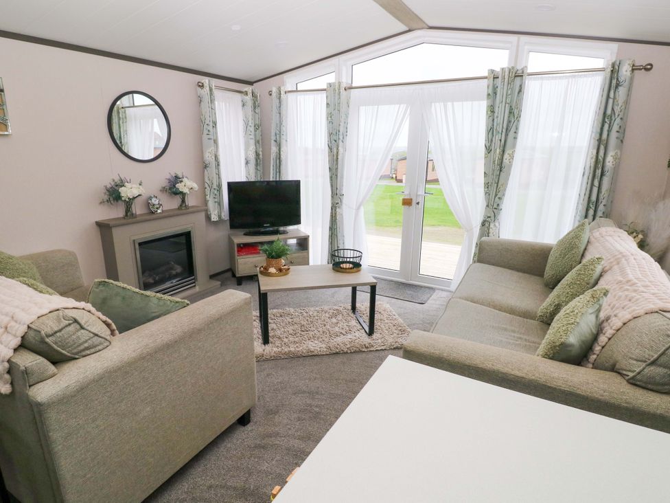 A living room with sofa and television at Oyster Lodge in Little Haven