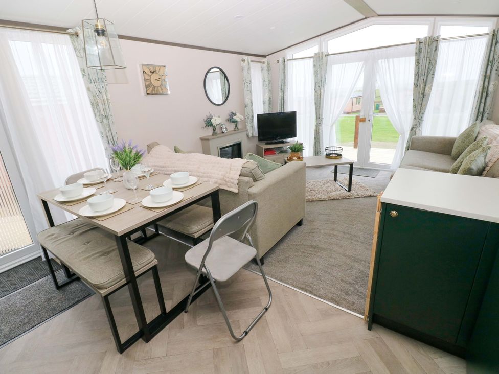 A living room with a dining table and sofa at Oyster Lodge in Little Haven