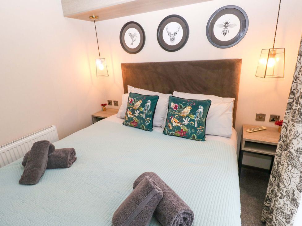 A bedroom with a bed and decorative pillows at Oyster Lodge Little Haven