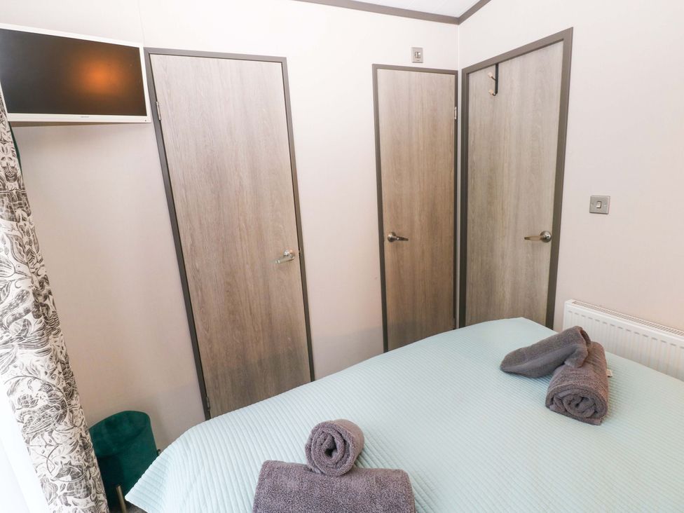 A bedroom with a bed and towels at Oyster Lodge in Little Haven