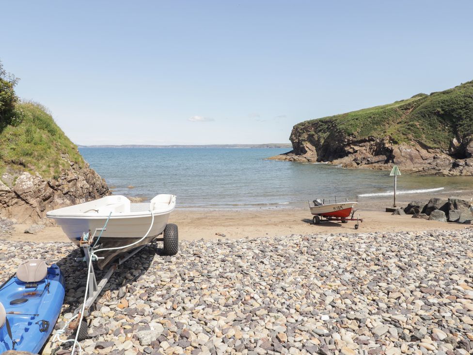 Two boats on a beach with rocks at Driftwood Lodge Hasguard Cross near Broad Haven