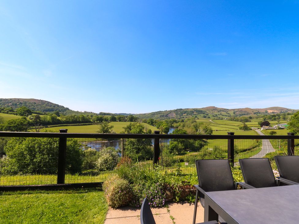 A patio with table and chairs overlooking fields river and hills at Pen Y Banc in Llanfaredd near Builth Wells