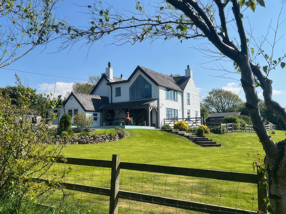 A house with a yard and trees at Cae Du in Dwyran near Niwbwrch (Newborough)