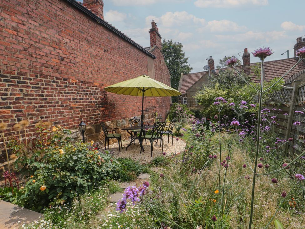 A garden with a table and chairs under an umbrella at Red Grouse Cottage in Guisborough