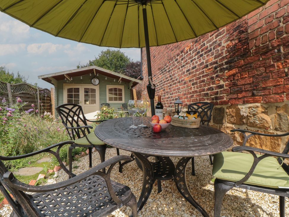 A garden with a table and chairs under an umbrella at Red Grouse Cottage in Guisborough