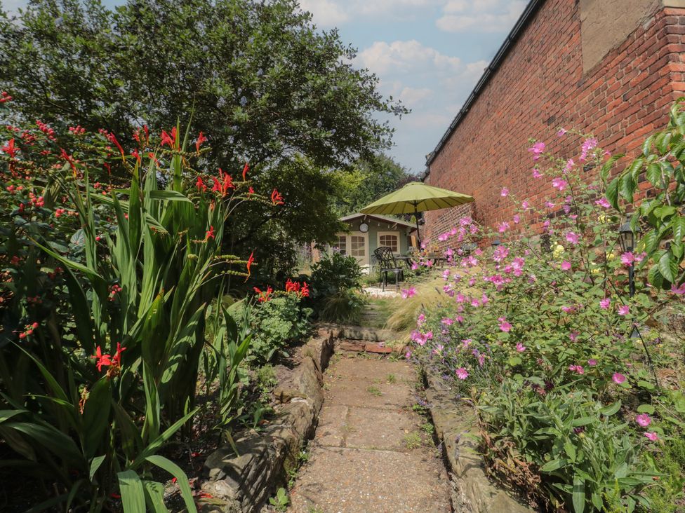 A garden with flowers and a path leading to seating at Red Grouse Cottage in Guisborough