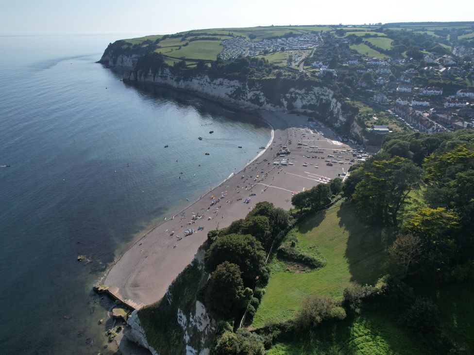 An aerial view of a beach with people on the shore cliffs and houses nearby at The Beach House in Beer
