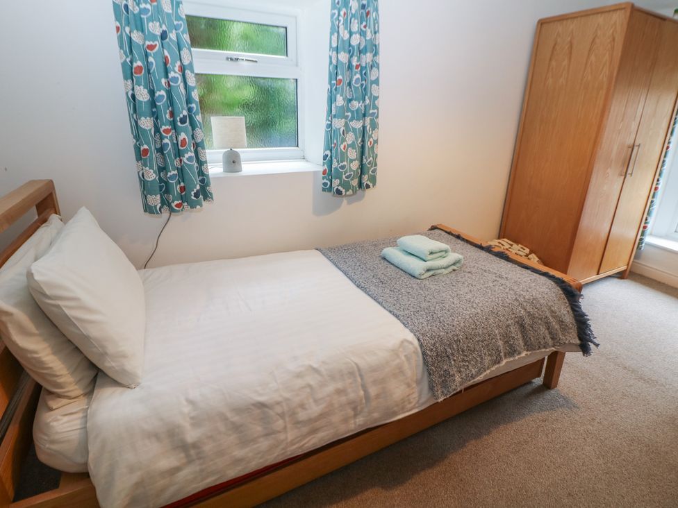 A bedroom with a single bed and a wardrobe at East Bank Cottage in Winster
