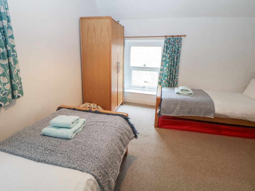 A bedroom with two beds and a wardrobe at East Bank Cottage in Winster