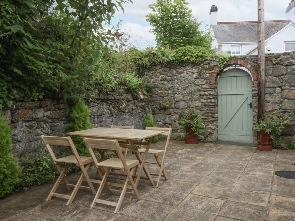A garden with a wooden table and chairs at The Old Tannery Beaumaris