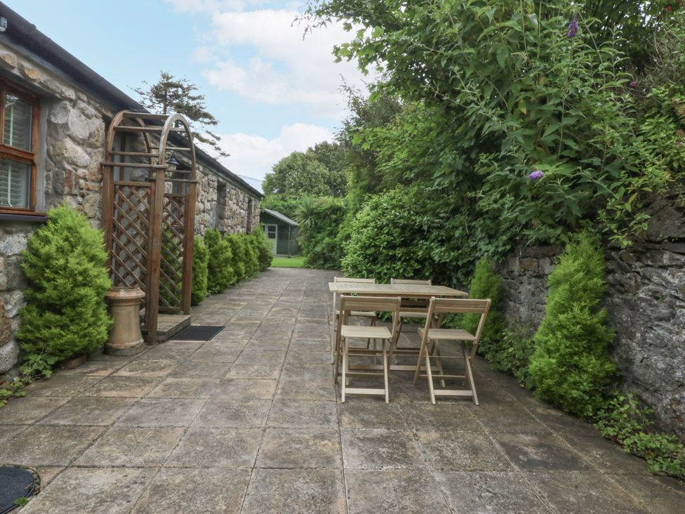 A garden with a table and chairs beside a stone wall at The Old Tannery Beaumaris