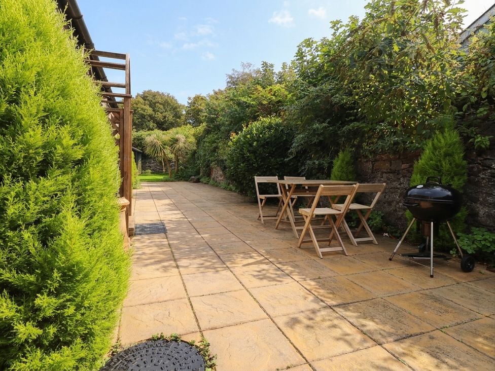 A garden with a table and chairs and a barbecue at The Old Tannery in Beaumaris