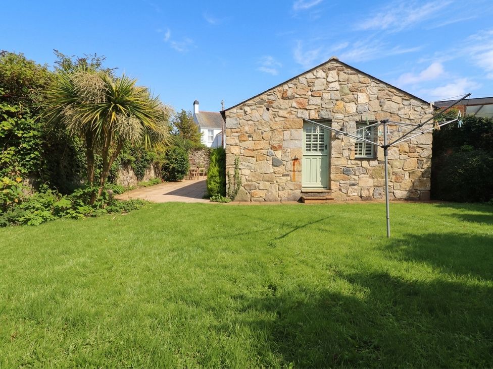 A stone building with a laundry line and grass at The Old Tannery in Beaumaris