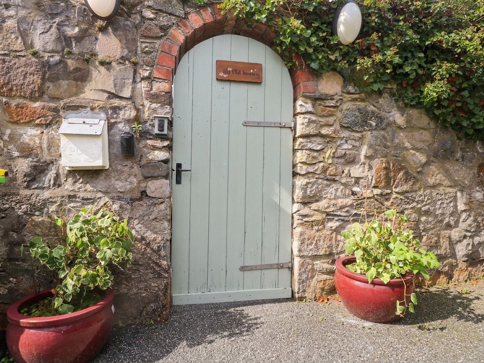 A door with a stone wall and plant pots at The Old Tannery Beaumaris