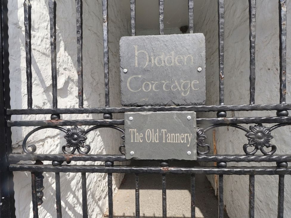 A gate with a sign for Hidden Cottage and The Old Tannery in Beaumaris
