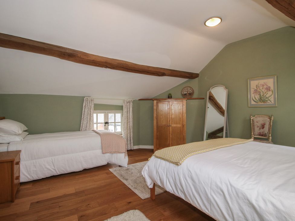 A bedroom with two beds and a wooden cupboard at Malt House