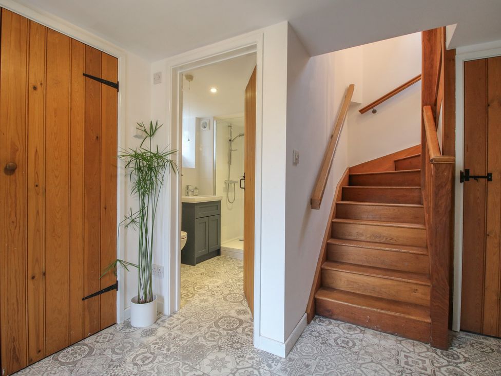 A hallway with stairs leading up and a bathroom door at Malt House