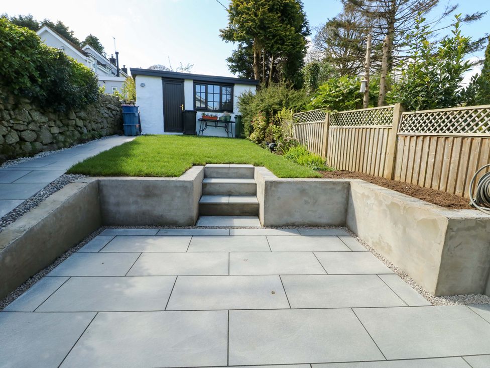 A garden with a grassy area, steps, and a shed at Craig Mawr, Benllech