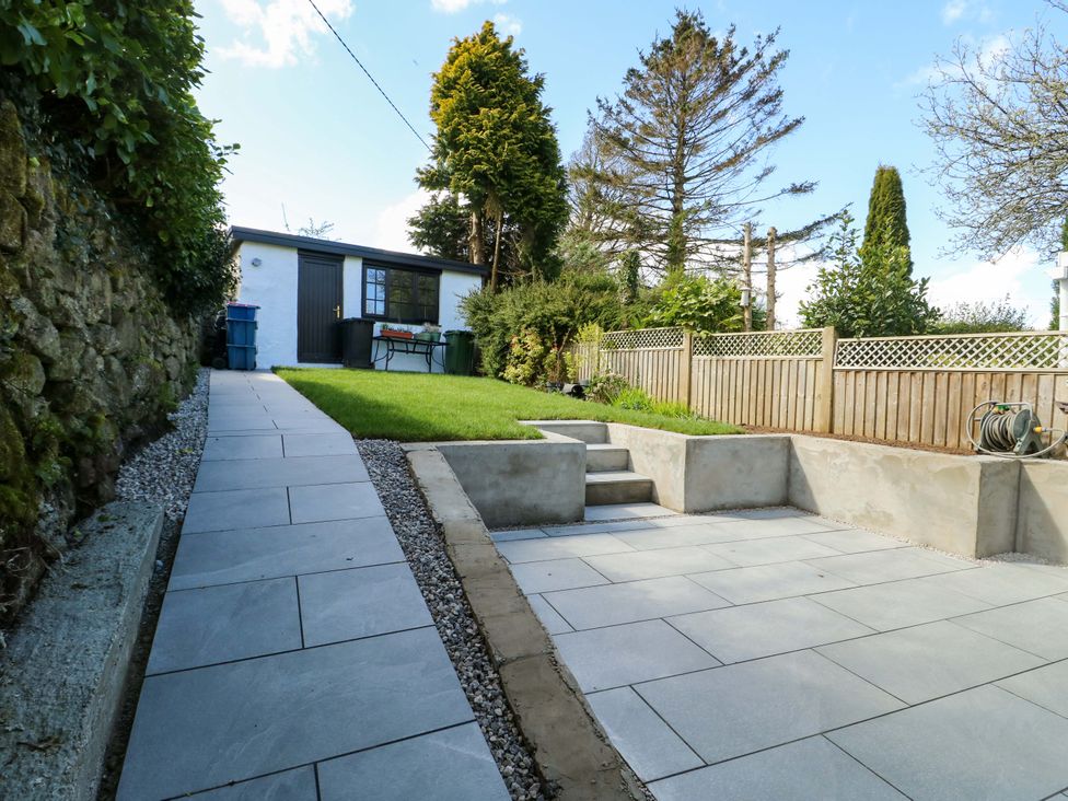 A garden with paving and grass at Craig Mawr in Benllech