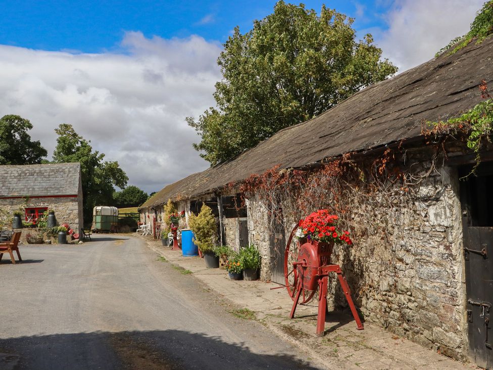An outdoor view of a pathway with buildings and flower pots at The Dairy in Ardfinnan, County Tipperary