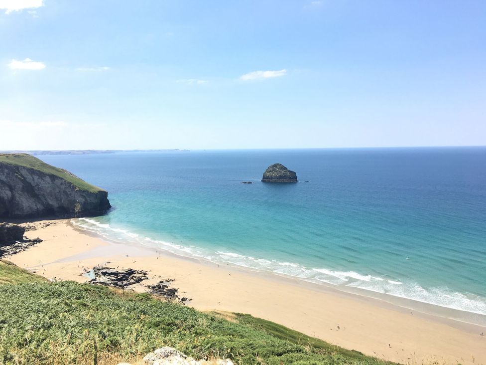 A beach with sand and a rock formation at Salty Sea Dog in Trebarwith Strand near Tintagel