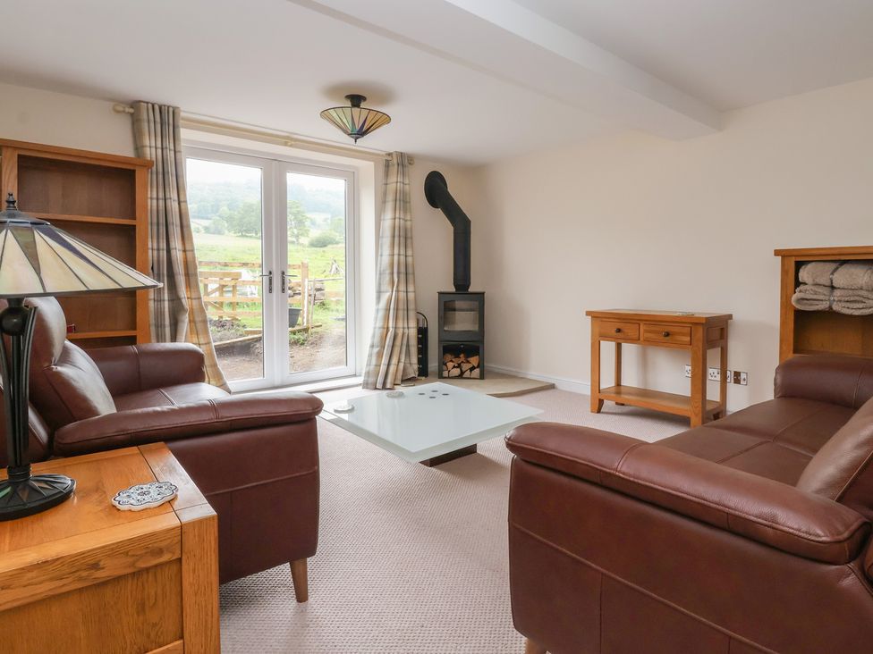 A living room with a sofa, coffee table, and wood stove at Cliffe House Cottage