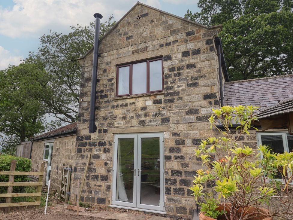 An outdoor view of a stone house with windows and a door at Cliffe House Cottage