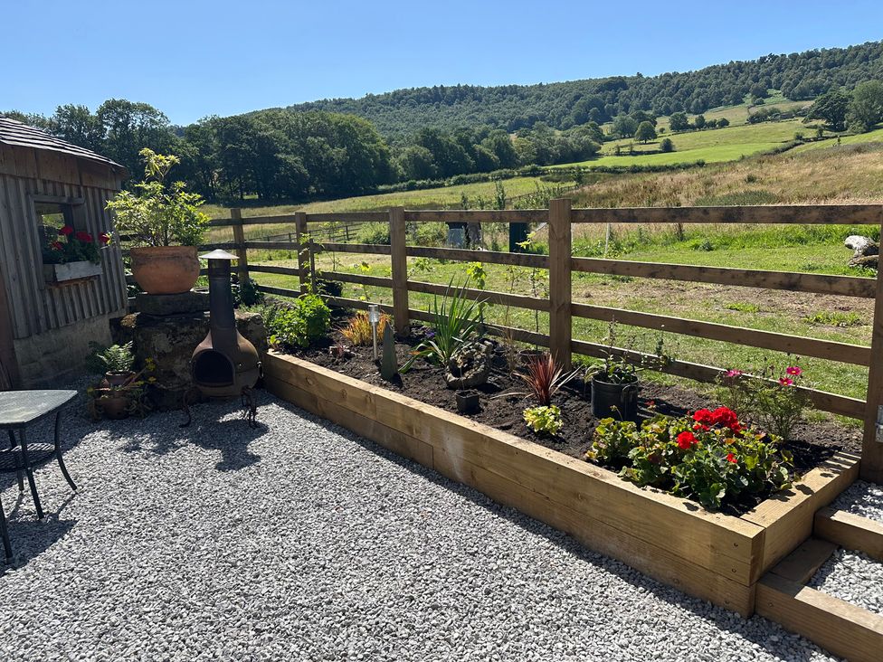 A garden with a flowerbed, gravel path and seating area at Cliffe House Cottage, Pateley Bridge