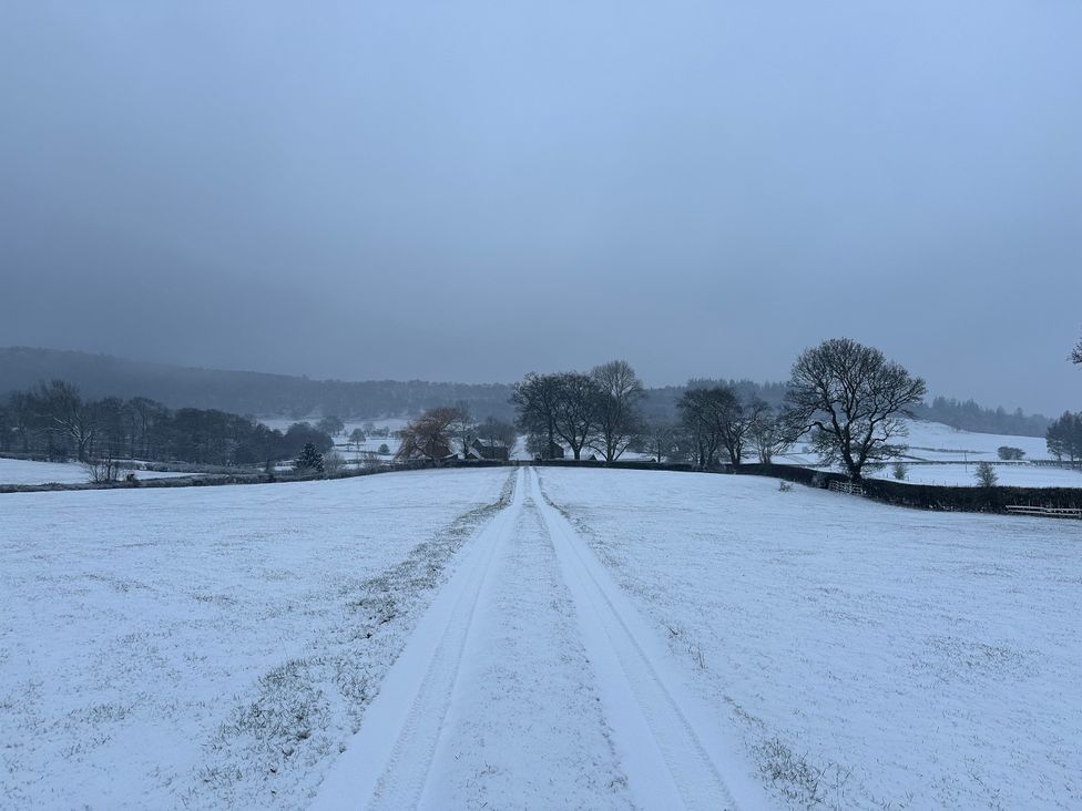 A snowy field with a path and trees at Cliffe House Cottage in Pateley Bridge