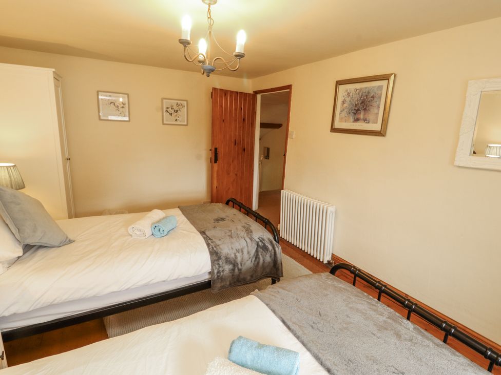 A bedroom with two beds, a radiator and a lamp at White House in Shap
