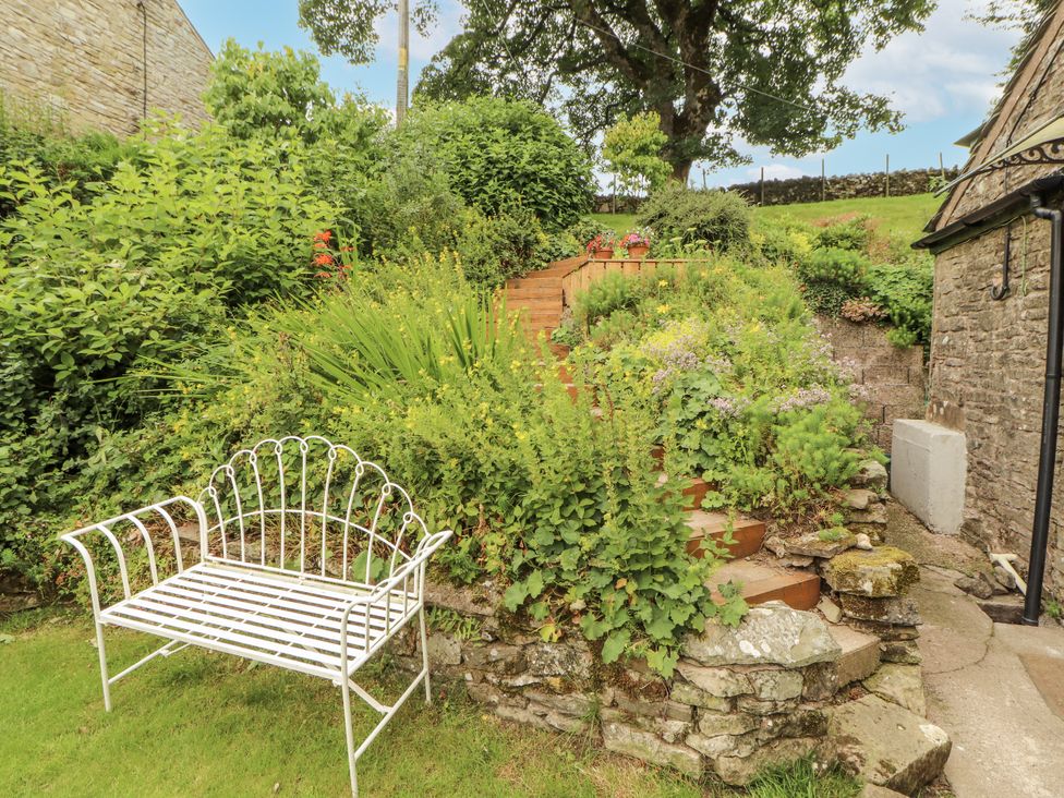 A garden with stone stairs and a white bench at White House in Shap