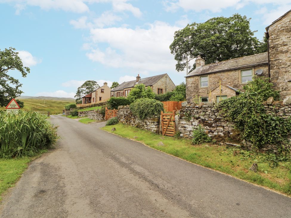 A view of houses along a road with a cattle warning sign at White House in Shap