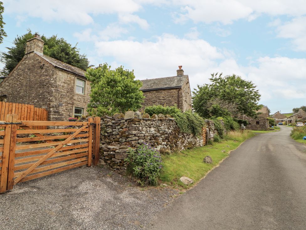 A stone house and wooden gate on a gravel driveway at White House in Shap