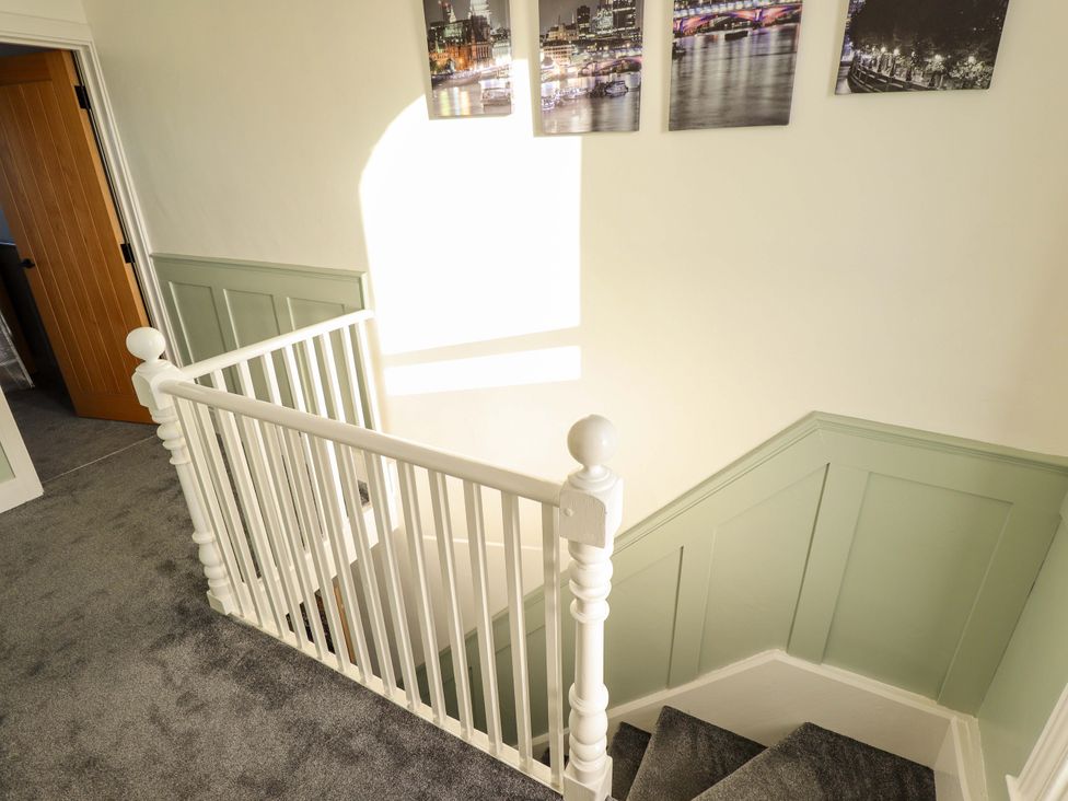 A staircase with white railing and photographs on the wall at 9 Alford Road
