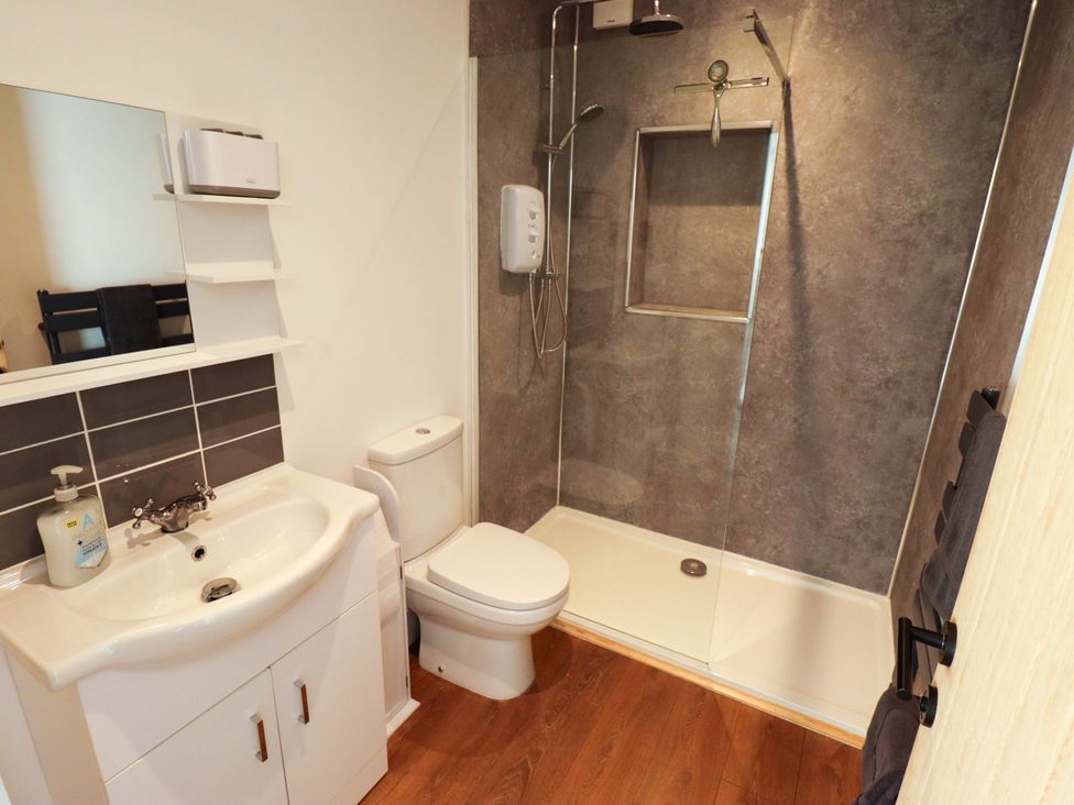 A bathroom with sink, toilet, shower, and mirror at 9 Alford Road