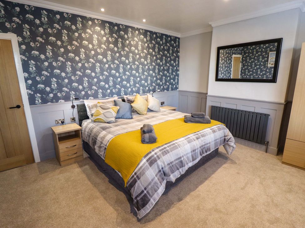A bedroom with a bed and decorative wallpaper at 9 Alford Road
