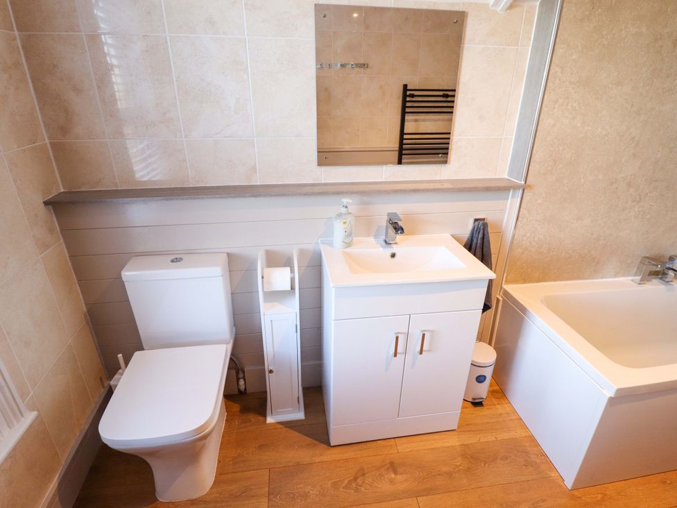 A bathroom with a toilet, sink, mirror and bathtub at 9 Alford Road
