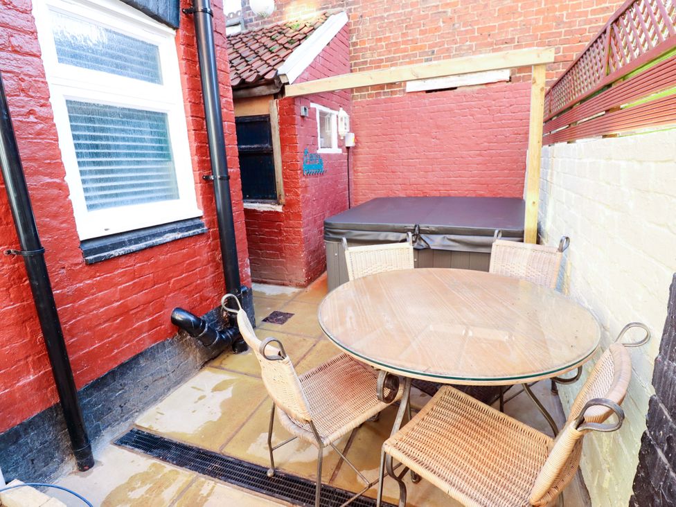 An outdoor seating area with a table and chairs and a hot tub at 9 Alford Road