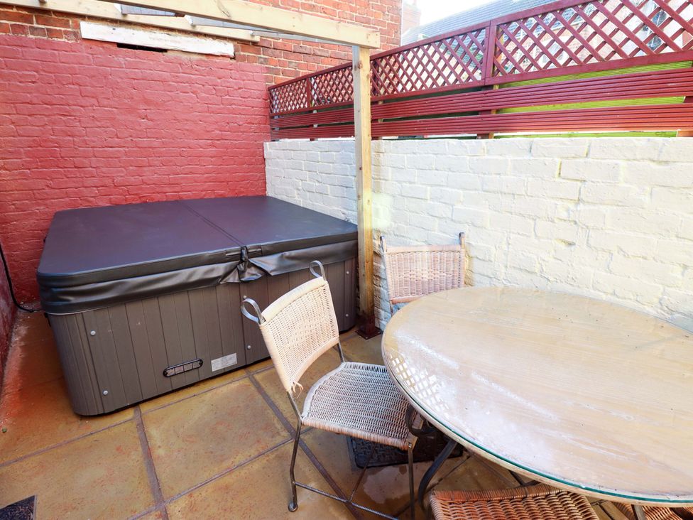 An outdoor space with a hot tub and a table with chairs at 9 Alford Road