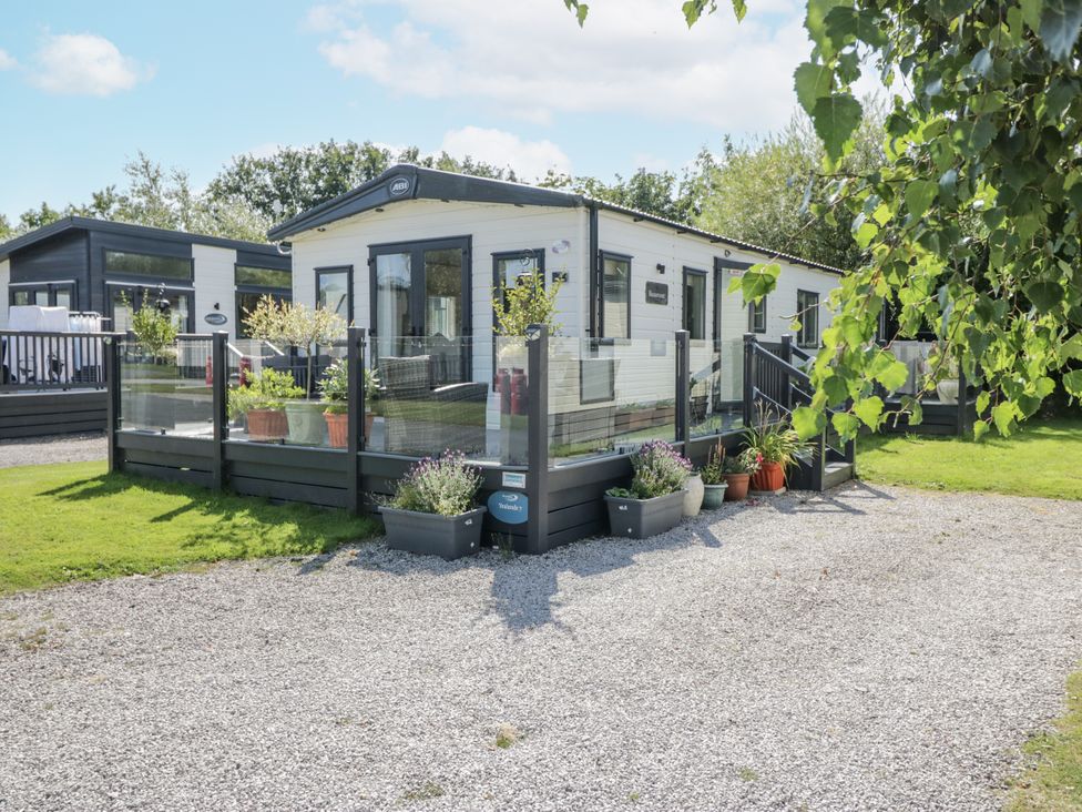 A mobile home with a deck and plants at Lilac Lodge in Carnforth