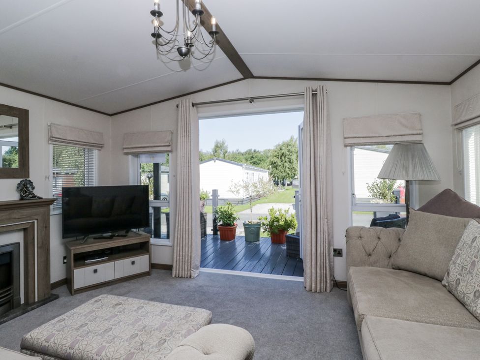 A living room with a television and sofa at Lilac Lodge in Carnforth
