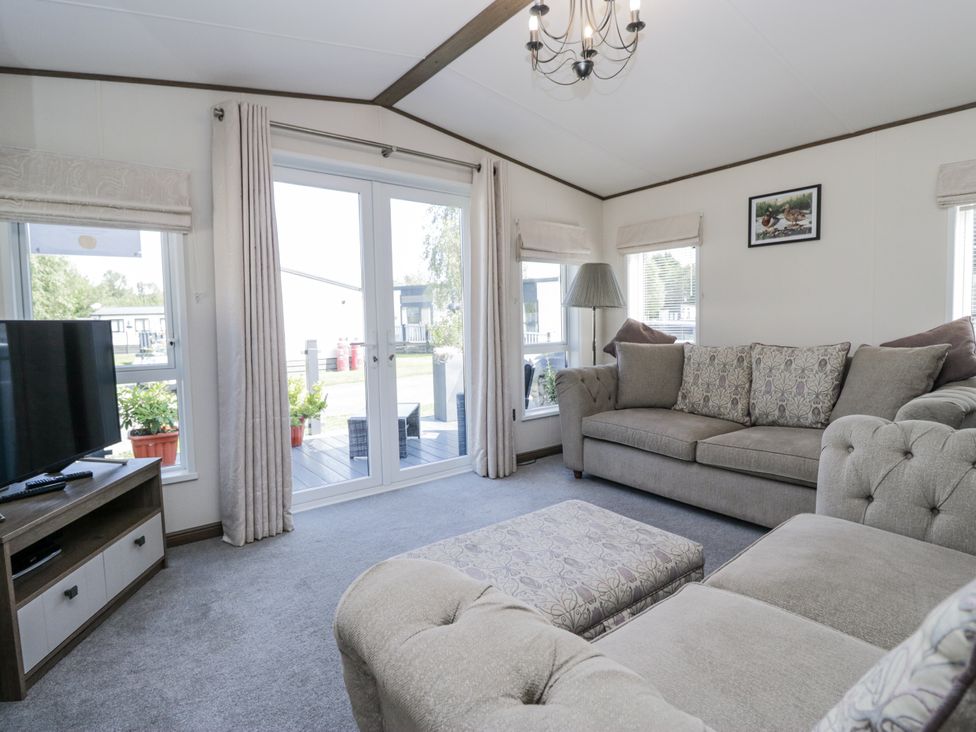 A living room featuring a sofa and television at Lilac Lodge in Carnforth