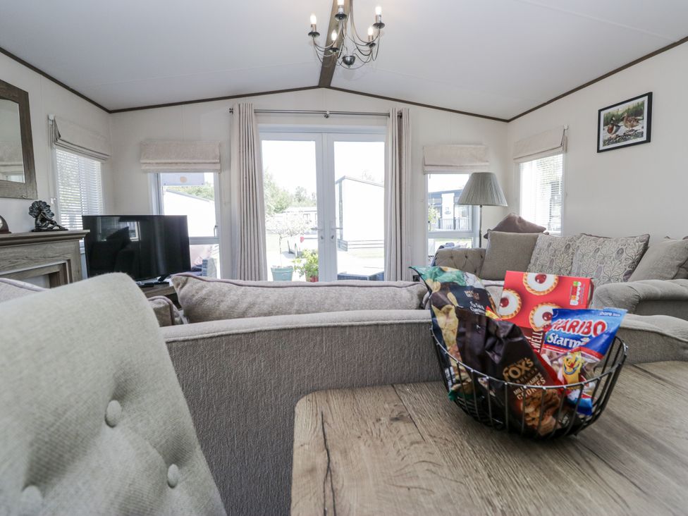 A living room with a television and a basket of candies at Lilac Lodge in Carnforth