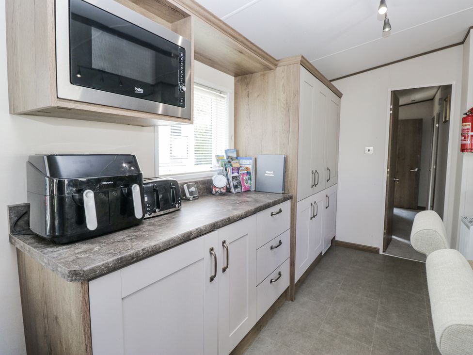 A kitchen with appliances and cabinets at Lilac Lodge Carnforth
